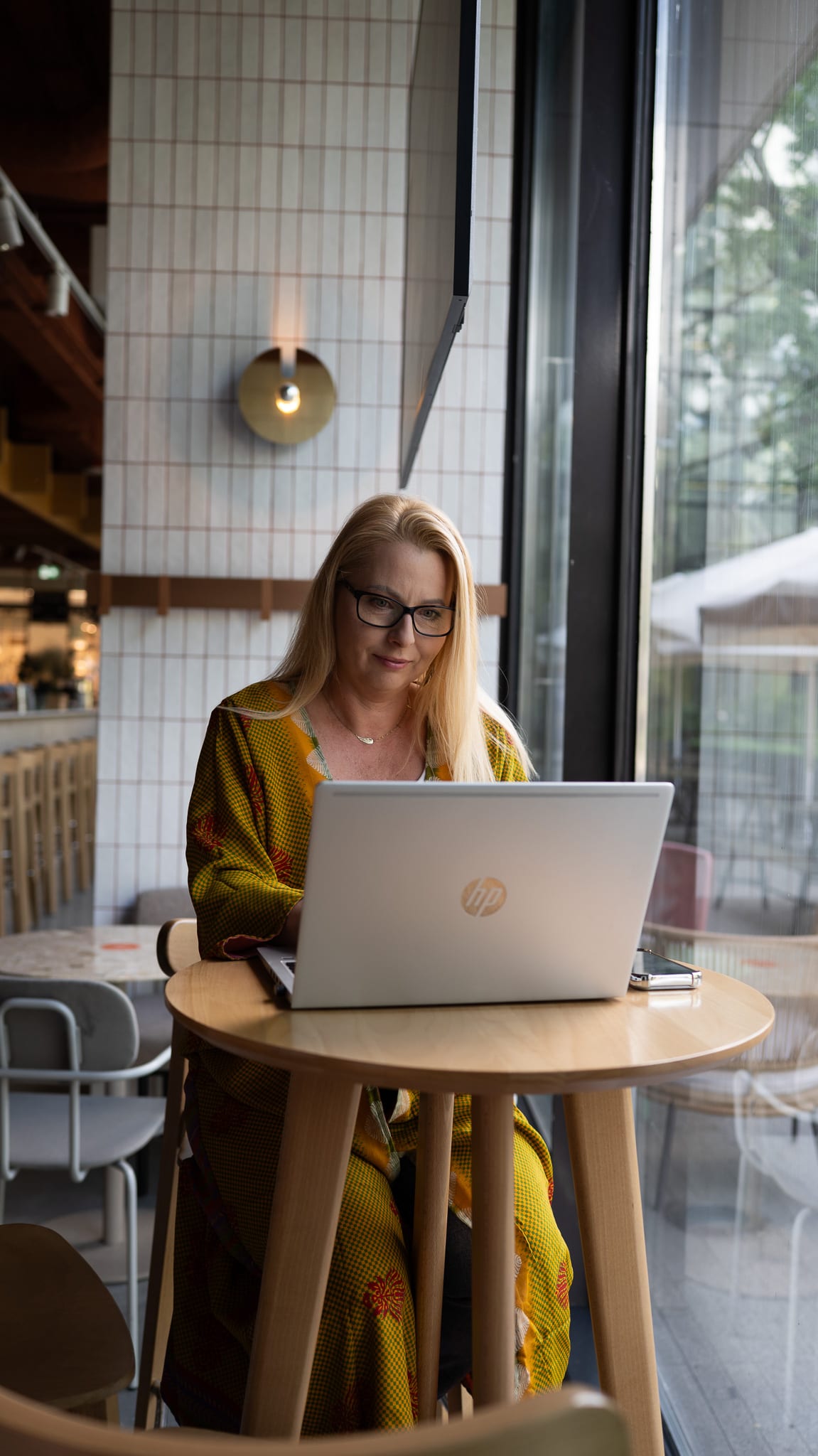 Sesja biznesowa — kobieta podczas pracy przy laptopie przy oknie